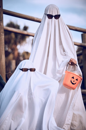 Halloween, friends and ghost costume for fun, festival and celebration while bonding at park, happy and cool. Spooky, dress up and event with people in horror, fantasy and glasses while celebratingの写真素材