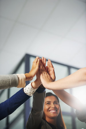 To another success. a group of businesspeople high fiving in an office.の写真素材