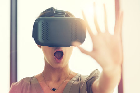 The artificial has never felt so real. a young businesswoman wearing a VR headset while connecting to a user interface in an office.の写真素材