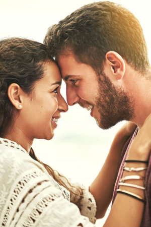 Looking deep into her eyes. an affectionate young couple enjoying their time on the beach.