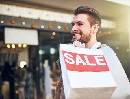 I go where the sale is. a young man holding a shopping bag.の写真素材