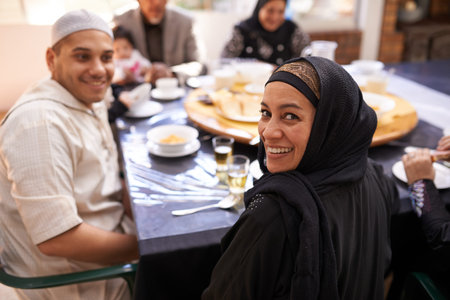 Breaking fast as a family. Portrait of a muslim woman looking back while enjoying a feast with her family.の写真素材