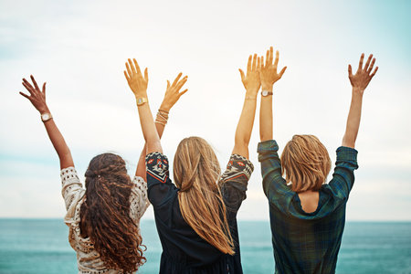 Set yourself free. Rear view shot of a group of friends standing with their arms outstretched outside.の写真素材