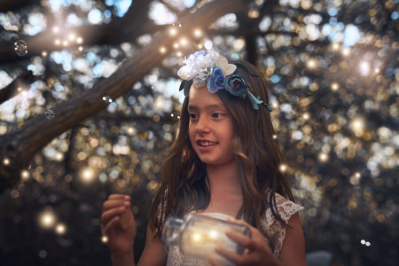 Days become magical when the fireflies come out to play. a little girl catching fireflies in a jar outside.の写真素材