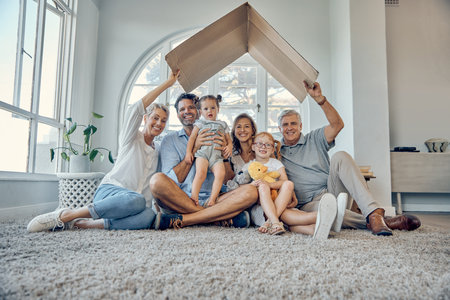 Big family, children and insurance with a mother, father and grandparents sitting under cardboard in the living room in home together. Kids, love and cover with parents and senior people in houseの写真素材