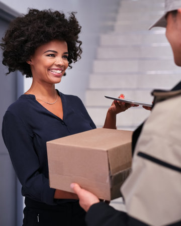 A happy businesswoman accepting a package from a courier in the office.の写真素材