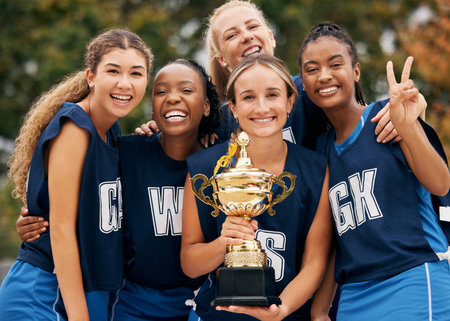 Women, team and winner trophy in fitness game, training match or exercise competition on netball sports field. Portrait, happy smile or sports award for teamwork diversity or friends workout successの写真素材