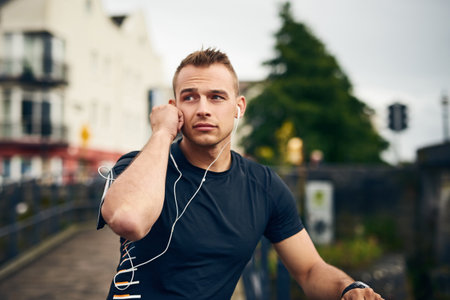 A sporty young man taking a break while exercising outdoors.の写真素材