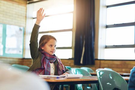 Shes always got an answer. an adorable elementary schoolgirl raising her hand in class.の写真素材