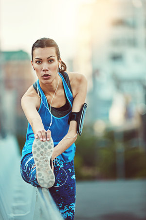Stretching her limits. sporty young woman stretching before her run.