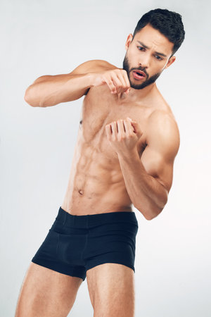 Body, muscle and boxing with a man athlete in studio on a gray background for sports or fitness. Healthy, muscular and training with a macho male boxer inside for exercise or a bodybuilding workoutの写真素材