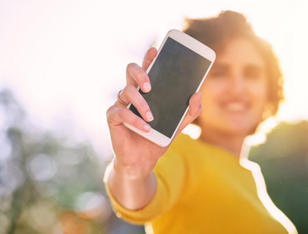 Advertise your new app here. an unrecognizable young woman using showing you a smartphone.の写真素材