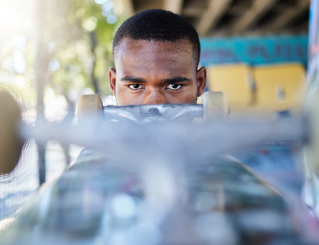 Portrait, skateboard and black man in city, street or outdoors ready for skating practice. Skateboarding sports, exercise and serious young male preparing for training or fitness workout in town.の写真素材