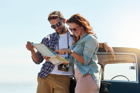 Where should we stop next. an affectionate couple looking at a map while enjoying a roadtrip.