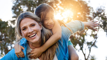 One on one time with her little girl. Portrait of a happy mother and daughter enjoying a piggyback ride outdoors.の写真素材