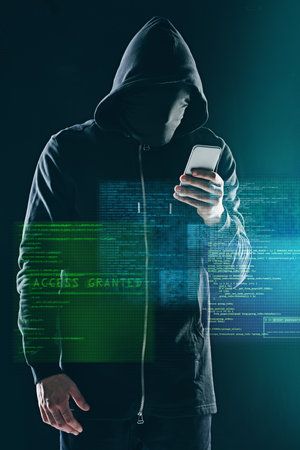 Hacking computers is so last year. an unidentifiable computer hacker using a smartphone while standing against a dark background.の写真素材