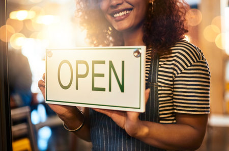 Well be waiting for you. Closeup shot of an unrecognizable woman hanging up an open sign in her store.の写真素材