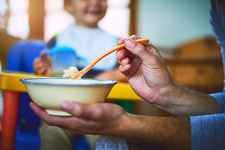Its that time of the day to feed your belly. an unrecognizable single father feeding his baby at home.の写真素材