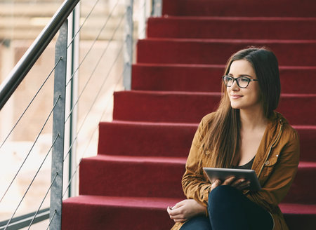 Expanding her mind through study. an attractive young university student studying while sitting on a staircase on campus.の写真素材