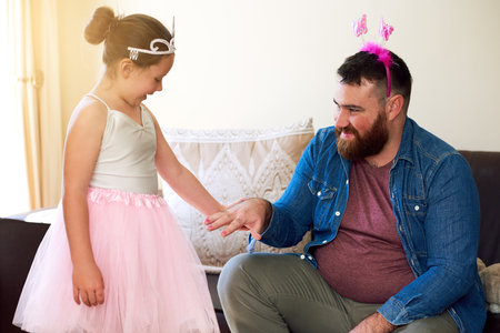Getting a girly makeover just to see her smile. an adorable little girl painting her fathers nails at home.の写真素材