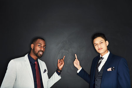 We suggest you take a look at this. Portrait of two young businessmen pointing against a dark...