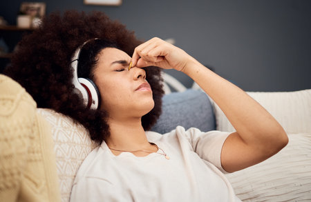 Headache, pain and woman with headphones of sofa tired, exhausted and trying to relax. Stress,...