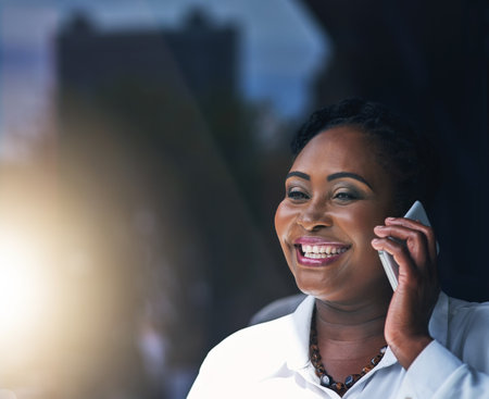 A happy businesswoman answering her cellphone in the office.の写真素材