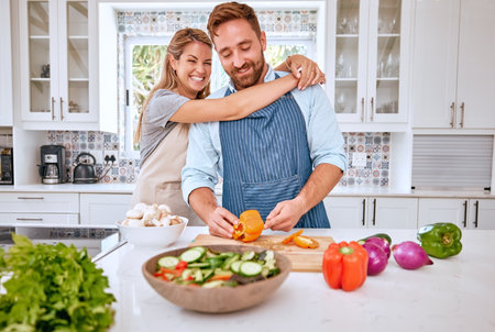 Happy couple, cooking and helping with vegetables, food and dinner in kitchen with love, care and support in happy marriage. Man and woman busy with a meal, salad or vegan diet for healthy lifestyleの写真素材