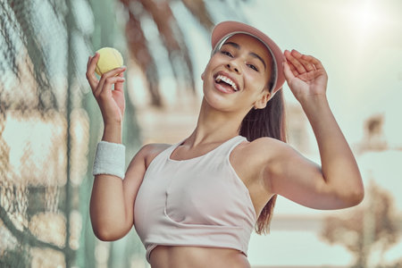 Happy, woman and tennis ball with smile for sports, exercise or fun workout in the summer outdoors. Portrait of female in sport fitness smiling for healthy cardio, tennis or training at the courtの写真素材