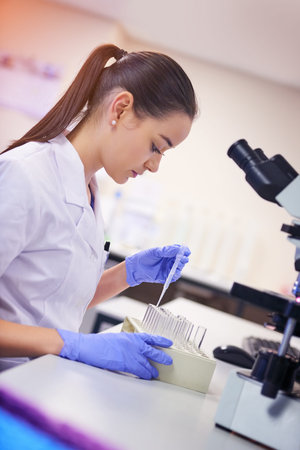 Making medical advances with her expertise. a young scientist transferring liquid from a pipette to...