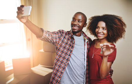 Another milestone worth sharing with the world. a young couple taking a selfie in their new home.の写真素材