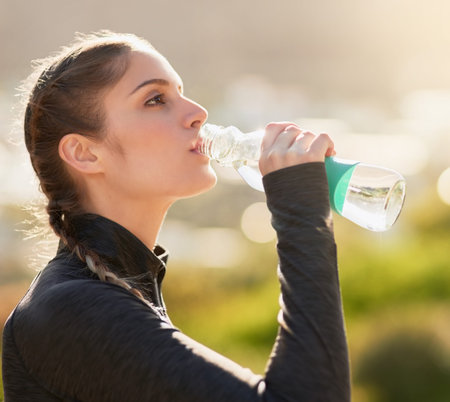 Staying hydrated. an attractive young woman drinking water during her workout.