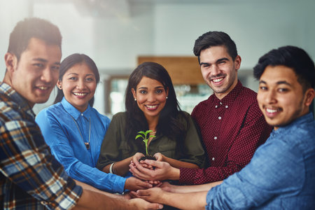 Nurturing creativity. Portrait of a team of designers holding a plant growing in soil.