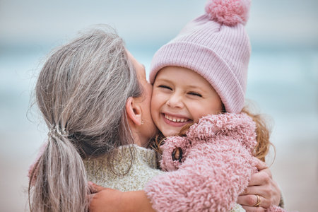 Happy family, beach and mother and child hug, bond or enjoy fun quality time together while relax on ocean sand. Love, peace and outdoor winter freedom for woman, mom or mama with kid girl in natureの写真素材