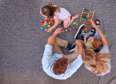 Family, children and learning with education toys, blocks and abacus for color game with mom and dad on floor. Man and women parents with kids for learning, development and playing on home carpetの写真素材