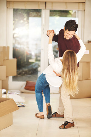 Having the first dance in their new home. Full length shot of an affectionate young couple dancing while moving into a new home.の写真素材
