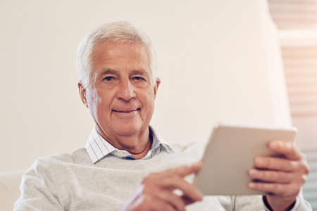 Its how I catch up on the latest news. Portrait of a senior man using a digital tablet at home.