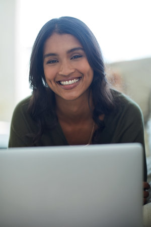 Social medias got me smiling. Portrait of an attractive young woman using her laptop while sitting...