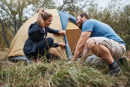 Camping, tent and love with a couple in nature for fun, adventure or bonding together in the wilderness. Forest, travel and hiking with a man and woman setting up their campsite on a weekend getawayの写真素材