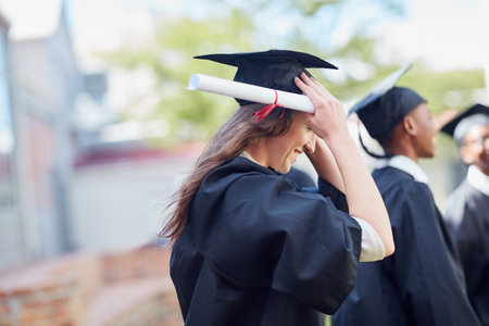 Heading into the world, diploma in hand. a happy group of students standing outside on their...