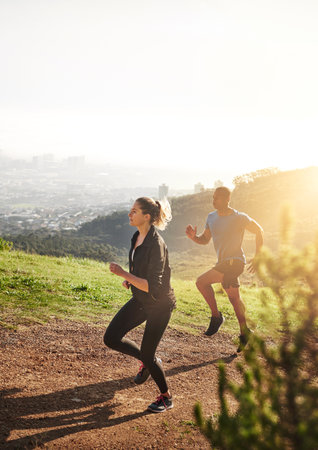 Yeah I run like a girl, try to keep up. a sporty couple out running on a mountain road.の写真素材