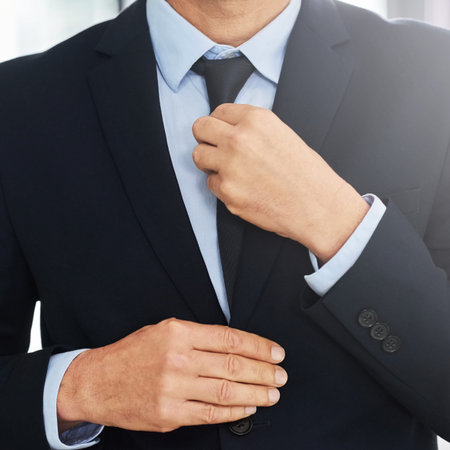 Looking suave and successful. Closeup shot of a mature businessman straightening his tie while...