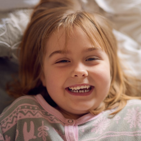 Let there be laughter. Portrait of a cute little girl giggling while lying on her bed at home.の写真素材