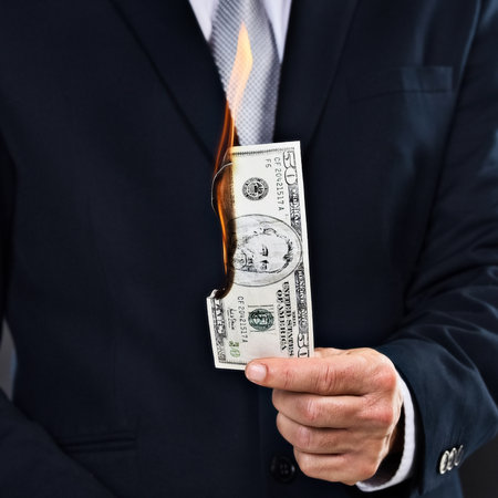 Hes got money to burn. a businessman holding a burning bank note.の写真素材