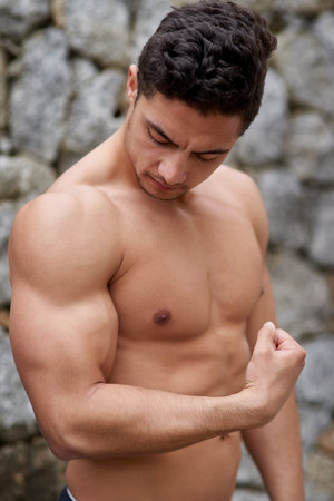 His biceps are bulging. a handsome young man flexing outside.