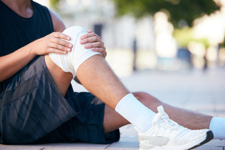 Knee injury pain, runner or man hurt from fitness, exercise or sports cardio workout for athlete healthcare. Accident emergency, ground floor or legs of training person with medical first aid bandageの写真素材