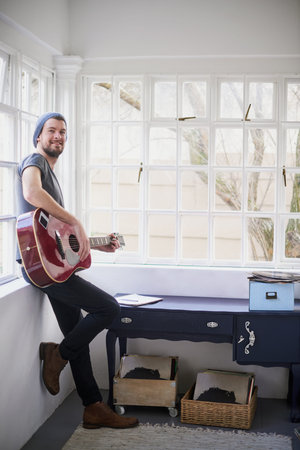 Songs so sweet youll feel serenaded. Portrait of a handsome young man playing a guitar at home.