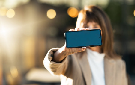 Hands, business woman and phone with green screen for advertising, marketing or promotion. Mockup space, professional lady and closeup of smartphone, cellphone or mobile device with chroma key screenの写真素材