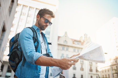 Travel is an investment in yourself. a young man looking at a map while touring a foreign city.の写真素材