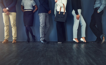 Your appearance is part of the interview. Cropped studio shot of a group of well dressed businesspeople standing in line while waiting to be interview.の写真素材